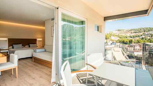 Ett hotellrum med två sängar och en sittmöbel, med en anslutande balkong där det finns bord och stolar samt utsikt över en grönskande kulle. (AI-genererad text)