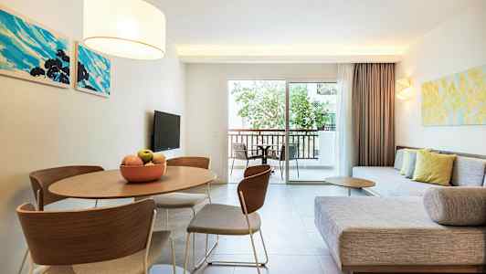 Ett modernt vardagsrum med soffa, bord och stolar samt en balkong med utsikt. (AI-genererad text)