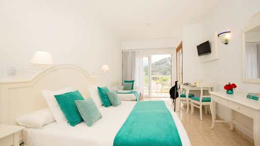 Hotellrum med vit inredning och turkosa textilier. (AI-genererad text)