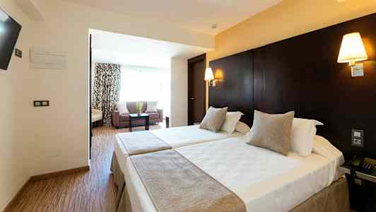 Hotel rum med två enkelsängar och ett sittområde. (AI-genererad text)