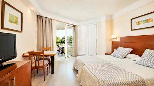 Bild på ett hotellrum med två enkelsängar, ett skrivbord med stolar och en balkong. (AI-genererad text)