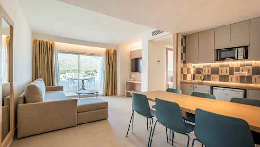En modern lägenhet med vardagsrum, matplats och kök. Det finns stora glasdörrar som leder till en balkong. (AI-genererad text)