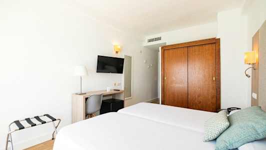 Hotellrum med två enkelsängar, skrivbord, stol, TV och garderob. (AI-genererad text)