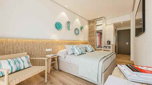 Ett hotellrum med en dubbelsäng, sittmöbel och öppet garderobsutrymme. (AI-genererad text)