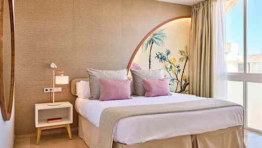 Ett modernt sovrum med en stor säng, dekorerad med prydnadskuddar och en väggmålning som föreställer palmer. (AI-genererad text)