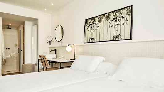 Ljust hotellrum med säng, skrivbord och badrum. (AI-genererad text)