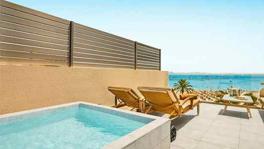 En terrass med liten pool, solstolar och ett bord med havsutsikt. (AI-genererad text)