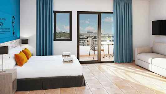 Ett hotellrum med två sängar, soffgrupp och ett bord på balkongen. (AI-genererad text)