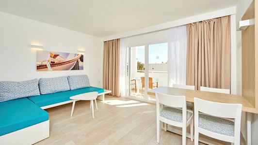 Ljust rum med blå soffa, ett bord med stolar och glasdörr till balkongen. (AI-genererad text)