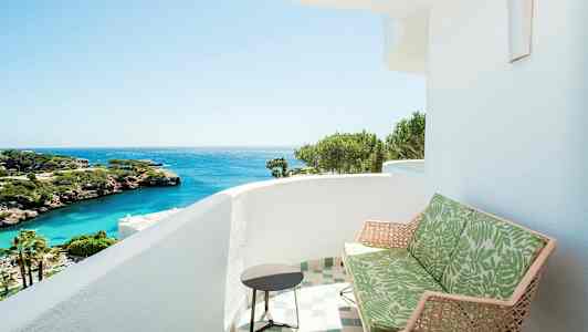 En balkong med utsikt över havet, med gröna växter och klippor. (AI-genererad text)