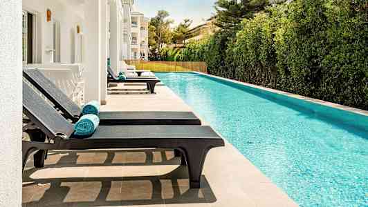 Soldäck med solstolar vid en pool. (AI-genererad text)
