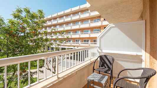 Balkong med två korgstolar och ett litet bord vid ett hotell. (AI-genererad text)