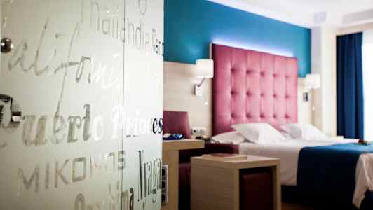 Hotellrum med färgglad inredning, säng och bord. (AI-genererad text)