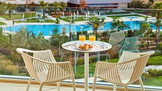 Två stolar vid ett bord med frukost i ett rum med utsikt över poolområdet. (AI-genererad text)