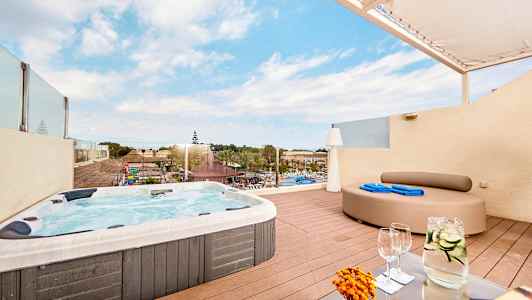Terrass med jacuzzi och utsikt över hotellområde med pool. (AI-genererad text)