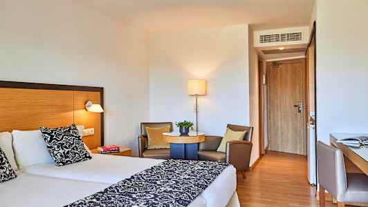 Hotellrum med två enkelsängar, sittgrupp och skrivbord. (AI-genererad text)