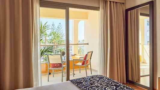 Hotellrum med balkong och utsikt över grönska. (AI-genererad text)