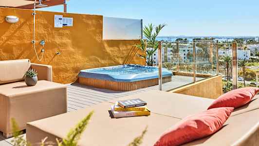 Terrass med bubbelpool, sittmöbler och öppen dusch med utsikt över omgivningen. (AI-genererad text)