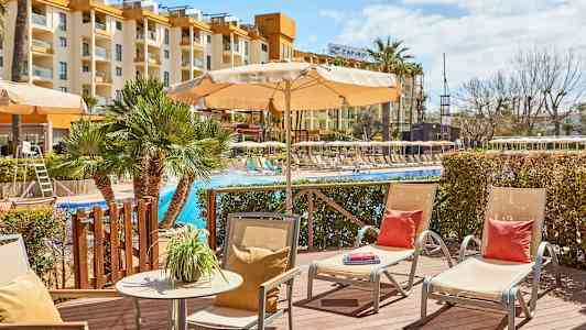 Utemiljö vid pool med solstolar och parasoller, hotellbyggnad i bakgrunden. (AI-genererad text)