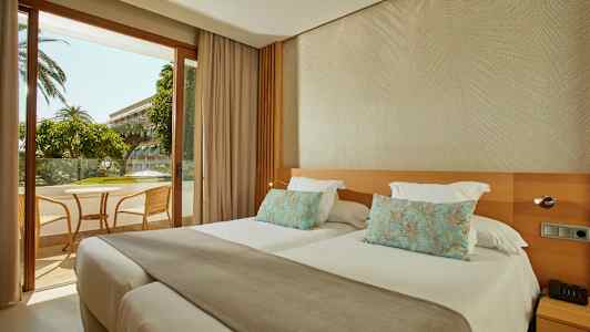 Hotellrum med två separata sängar och utsikt mot en möblerad balkong. (AI-genererad text)