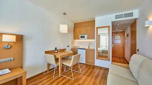 Ett hotellrum med köksdel och matsalsbord. (AI-genererad text)