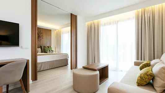 Ljus och välkomnande hotellrum med separat sovdel och vardagsrumsområde. (AI-genererad text)