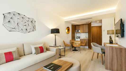 Ett ljust och modernt hotellrum med sittplats, skrivbord, soffa och ett litet kök. (AI-genererad text)