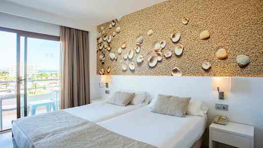 Hotellrum med två enkelsängar, dekorativ tavla med snäckor och balkong med utsikt. (AI-genererad text)