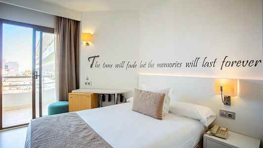 Hotellrum med en dubbelsäng, skrivbord och balkongdörr. (AI-genererad text)