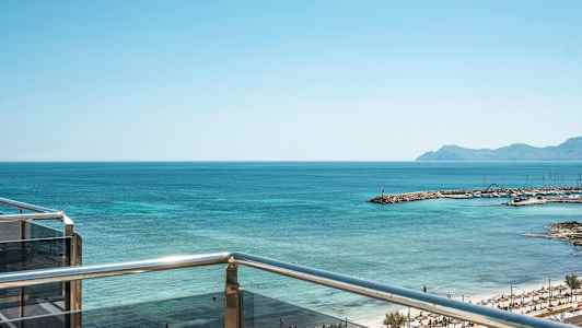 Utsikt från en balkong mot havet och en strand med solparasoller. (AI-genererad text)