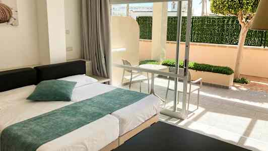 Modernt inrett hotellrum med säng och utsikt mot en privat terrass. (AI-genererad text)