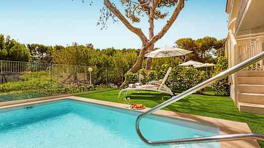 Utomhuspool med solstolar och parasoller samt grönska i bakgrunden. (AI-genererad text)