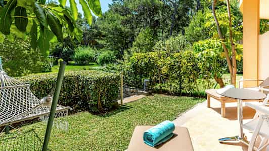 En terrass med solsängar och sittgrupp, utsikt över en trädgård med hängmatta. (AI-genererad text)