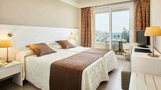 Hotellrum med två enkelsängar och balkong. (AI-genererad text)