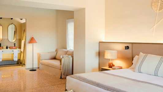 Ett stilrent hotellrum med en säng, soffa och ett öppet badrum. (AI-genererad text)
