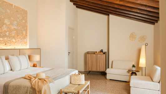 Ett inrett hotellrum med en säng, sittmöbler och ett skåp. Rummet har en varm, modern stil med beige och naturliga trädetaljer. (AI-genererad text)