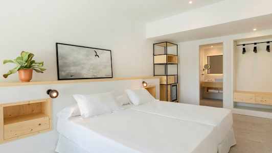 Ett ljust hotellrum med en dubbelsäng och inredning av trä. (AI-genererad text)