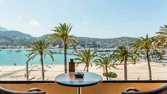 Utsikt från en balkong mot en strand med palmer och hav en solig dag. (AI-genererad text)