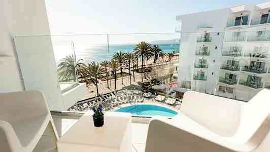 Utsikt från en balkong mot en pool, palmer och havet. (AI-genererad text)