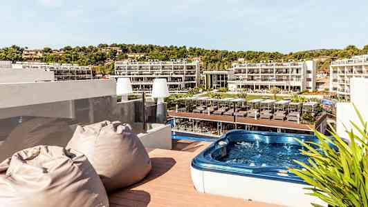 Terrass med bubbelpool och utsikt över hotellområde. (AI-genererad text)