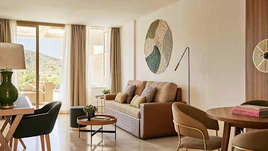 Vardagsrum med soffa, soffbord, matbord och stolar samt utsikt genom stora fönster mot natur. (AI-genererad text)