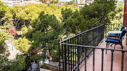 Balkong med bord och stolar mot en grönskande utsikt. (AI-genererad text)