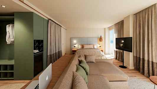 Modernt hotellrum med säng, soffa och TV framför stora fönster. (AI-genererad text)