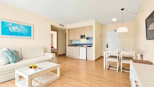 Vardagsrum med soffa, soffbord, matbord och ett pentry. (AI-genererad text)