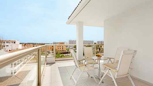 En balkong med bord och stolar samt utsikt över omgivande byggnader. (AI-genererad text)