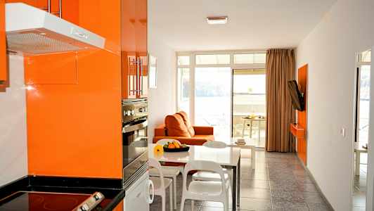 Modernt kök och vardagsrum med orange inredning och en utsikt mot havet. (AI-genererad text)