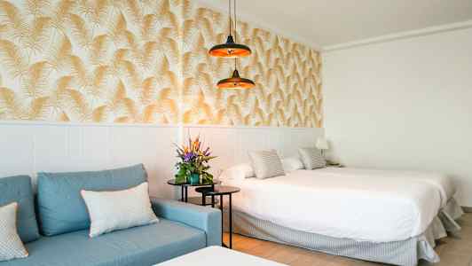 Hotellrum med blå soffa, dubbelsäng och dekorativ tapet. (AI-genererad text)