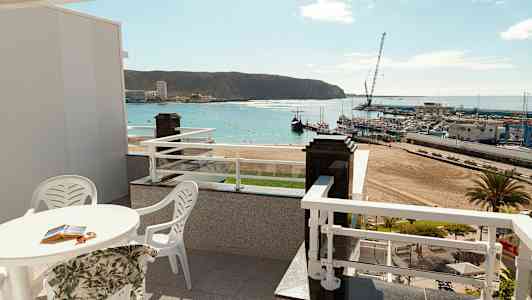 Terrass med utsikt över en strand och en hamn. (AI-genererad text)