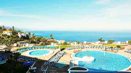 Bild av ett hotell med poolområde i förgrunden och havsutsikt i bakgrunden. (AI-genererad text)