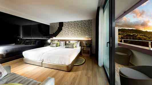 Modernt hotellrum med två sängar, en spegelvägg och balkong med utsikt över landskapet. (AI-genererad text)